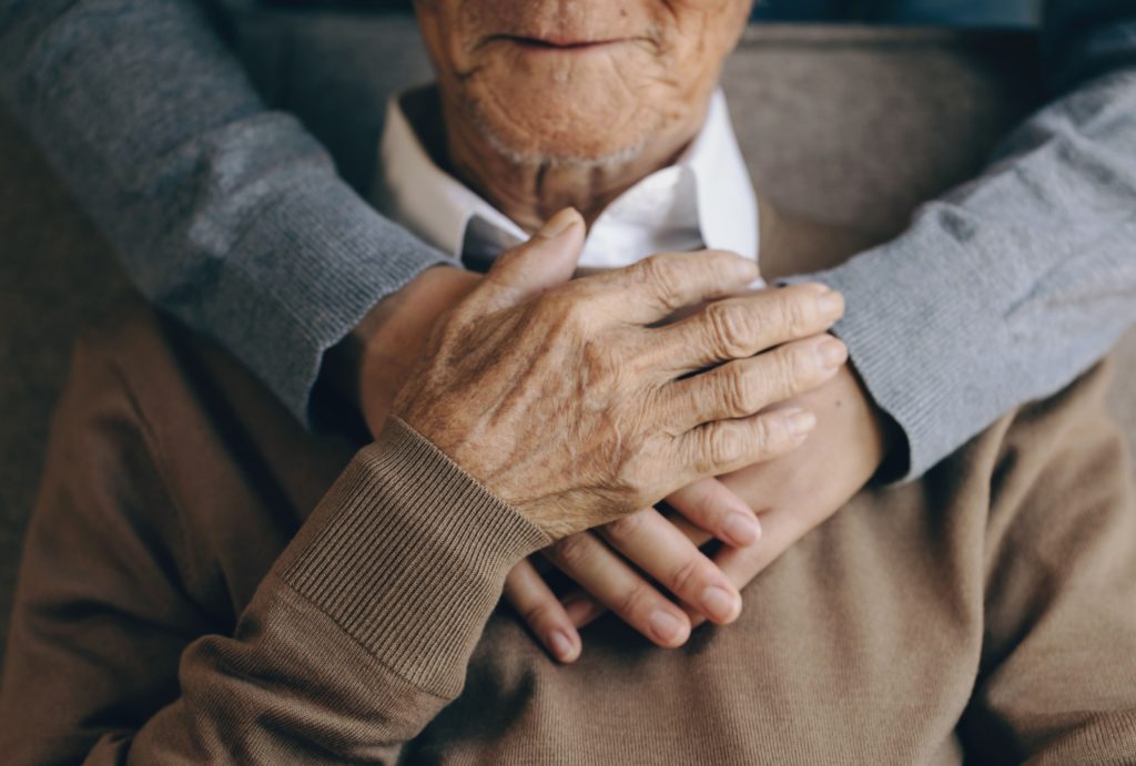 A closeup of someone embracing their senior loved one.